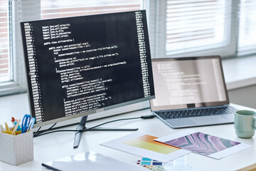 Background image of computer screen with code lines at software designer workplace by window