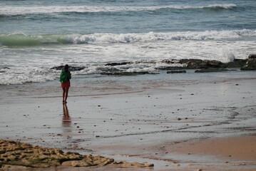 Lonely figure of a girl on the beach. Ocean coast. Walk alone.