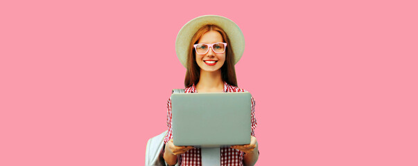 Portrait of modern young woman working with laptop on pink background