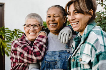 Multiracial senior farmer people gardening outdoor in home backyard terrace - Soft focus on left woman face Agriculture spring lifestyle concept