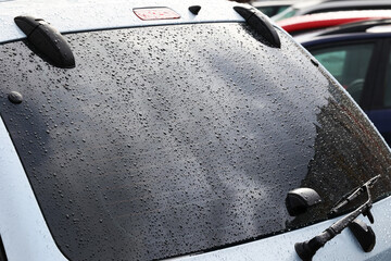 Krople deszczu - wody na karoserii samochodu i na szybie.