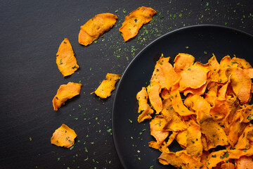 Healthy sweet potato chips on dark wood background