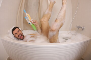 Adult man using water gun in the bathtub 