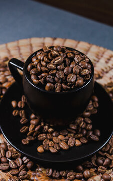 Black Coffee Cup Full Of Coffee Beans On Wooden Table In Dark Background