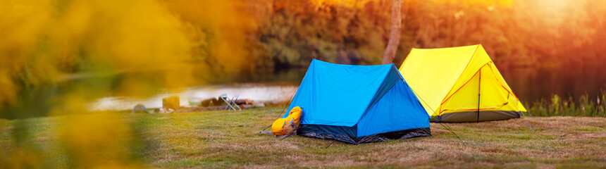 Panoramic view of the campground with colourful tents near the lake in wilderness park.