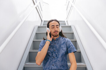 Young latin man relaxing listening to music through his headphones on the stairs of a ferry.