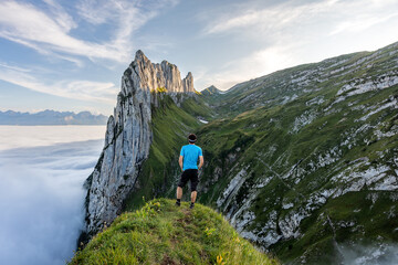 Fototapeta premium Hiking in the Switzerland. Man walking on the mountain trail. Fog in the valley.