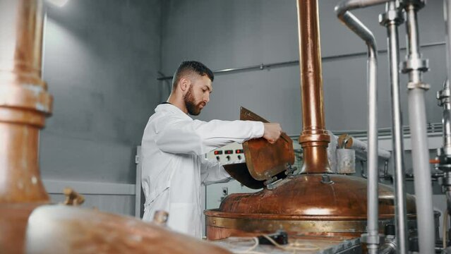 traditional equipment in modern brewery, technologist is controlling brewing process