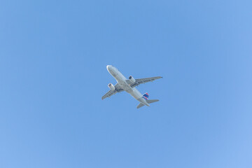 A jet plane flying in a blue sky between clouds. Transportation. Air travel.