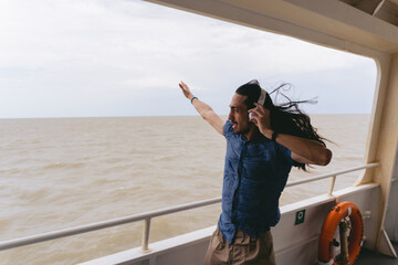 Young latin man with long hair feeling the wind while holding his headphones. Copy space.