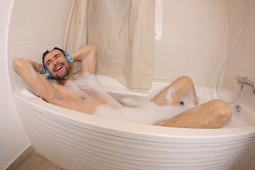 Man listening to music with headphones  in the bathtub