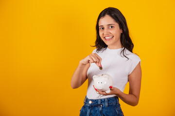 beautiful brazilian woman holding piggy bank and coin.