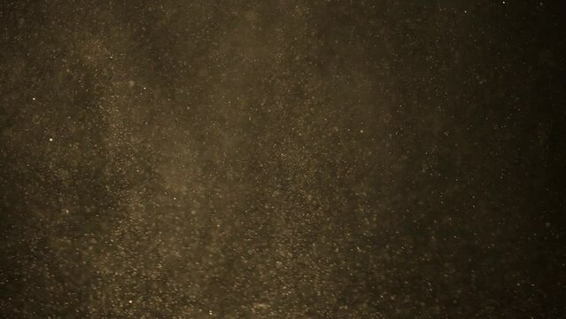 Golden dust particles and small debris fly in the air