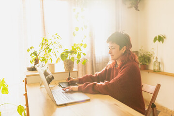 woman working, studying with laptop at home, redhead man with plants at sunset