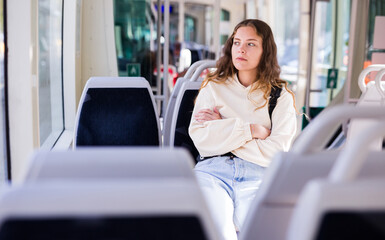 Portrait of a focused, looking into the distance, girl riding in public transport