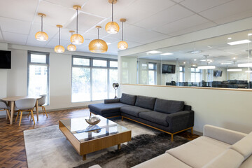 Empty creative office room with glass wall, couch and tv
