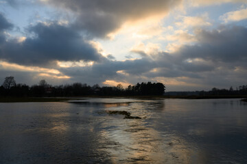 Sunlit clouds reflections. Sunset over river. Epic clouds reflection. 