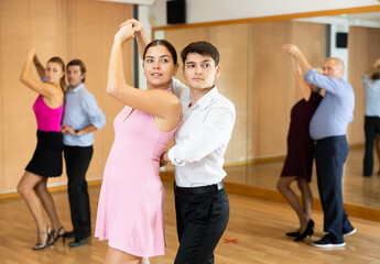 Couple of young dancers rehearsing ballroom dances in dance studio