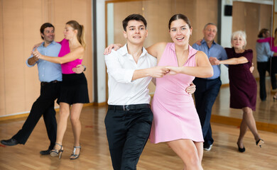 Couple of young dancers rehearsing ballroom dances in dance studio