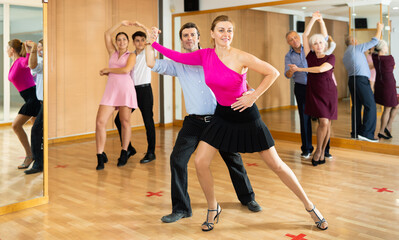 Couple of dancers rehearsing ballroom dances in dance studio