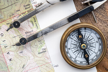 Topographical map on a wooden surface with compasses, measuring tool on top