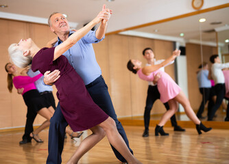 Fototapeta na wymiar active elderly people attend dance lessons for amateurs and learn to dance waltz in their free time