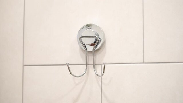 Hand removes, takes towel off the hook on the wall in bathroom. 