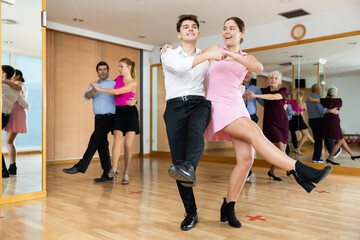 Couple of young dancers rehearsing ballroom dances in dance studio