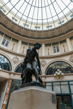Paris, France - February 10 2023: Dying Eurydice statue with Glass Cupola roof in the background at Colbert Gallery. This statue is a work of Charles-Francois Leboeuf, aka Nanteuil (French, 1792-1865)