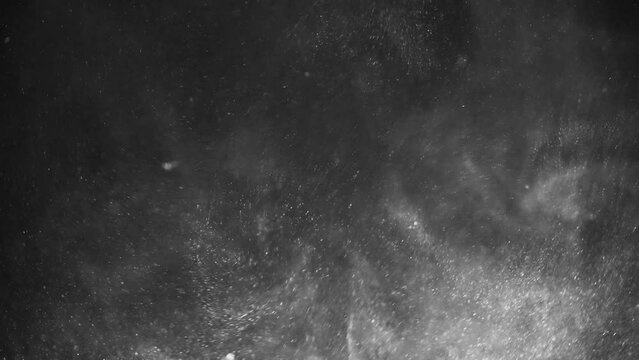 Dense dust particles fly in the air in slow motion on a black background macro close-up