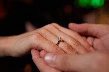 Young man putting ring on finger of his fiancee after marriage proposal, closeup.
