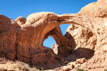 Three red rock arch formation in the desert of Arches National Park Utah with a clear blue sky.