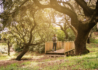 Man walking in a natural park with a backpack on his back with trees and a beautiful sunlight