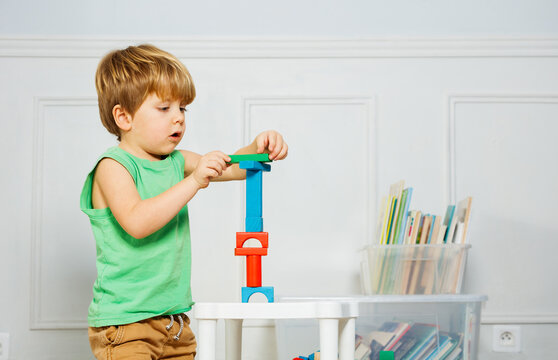 Young boy building block tower amidst books and toys