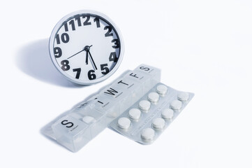 Pills, medicine dispenser, and a clock Isolated in a white background