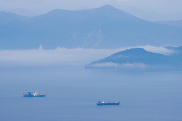 View of the ships in the bay. Mountains in the distance. Fog over the water. Beautiful morning seascape. Avacha Bay, Pacific Ocean. Kamchatka Peninsula, Far East of Russia.