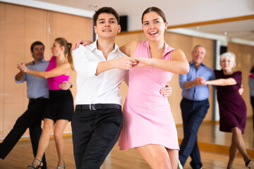Active young pair practicing Latino dance in training hall during dancing-classes. Pairs training ballroom dance