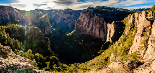 Obraz premium panoramic of long waterfall in a valley with sky and clouds, sun in the horizont, basaseachi chihuahua 