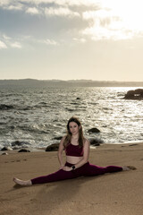 Fototapeta na wymiar beautiful young woman doing the splits on the beach in front of the sea