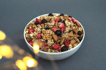 A bowl of muesli on a gray monochrome background, healthy food, healthy breakfast. With the glare...