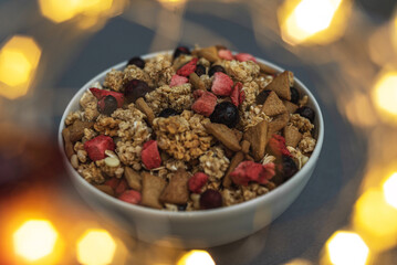 A bowl of muesli on a gray monochrome background, healthy food, healthy breakfast. With the glare of lights from the garland