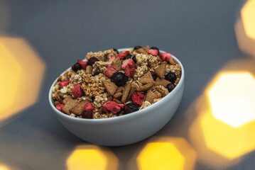 A bowl of muesli on a gray monochrome background, healthy food, healthy breakfast. With the glare of lights from the garland