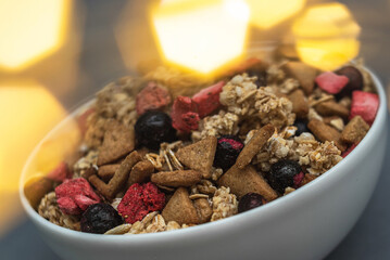 A bowl of muesli on a gray monochrome background, healthy food, healthy breakfast. With the glare of lights from the garland