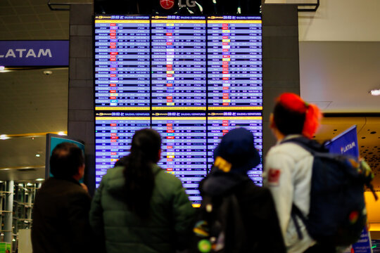 Bogota, Colombia - January 8, 2023: Passengers check their flight in front of the arrivals and departures screen at El Dorado airport