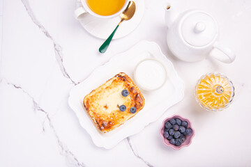 Cottage cheese casserole with blueberries and honey on a white table. Breakfast.