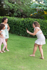 Naklejka premium Latin mother taking a photo of her daughters outdoors
