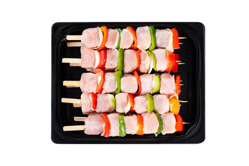Skewers with pieces of raw meat, red, yellow and green pepper, on white background.Uncooked mixed meat skewer with peppers.Top view.Close-up.