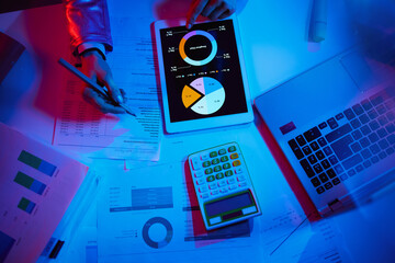 Upper view of modern woman with calculator working with graphs