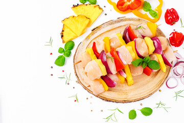 Uncooked meat skewer.Raw pieces of chicken skewers with pepper onion and pineapple white background.Skewers with pieces of raw meat, red, yellow pepper.Top view.Chicken Skewers breast fillet meat.