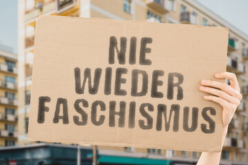 The phrase " Never again fascism " is on a banner in men's hands with blurred background. Determination. Enlightenment. Understanding. Responsibility. Dignity. Conscience. Integrity. Ethical. Honesty